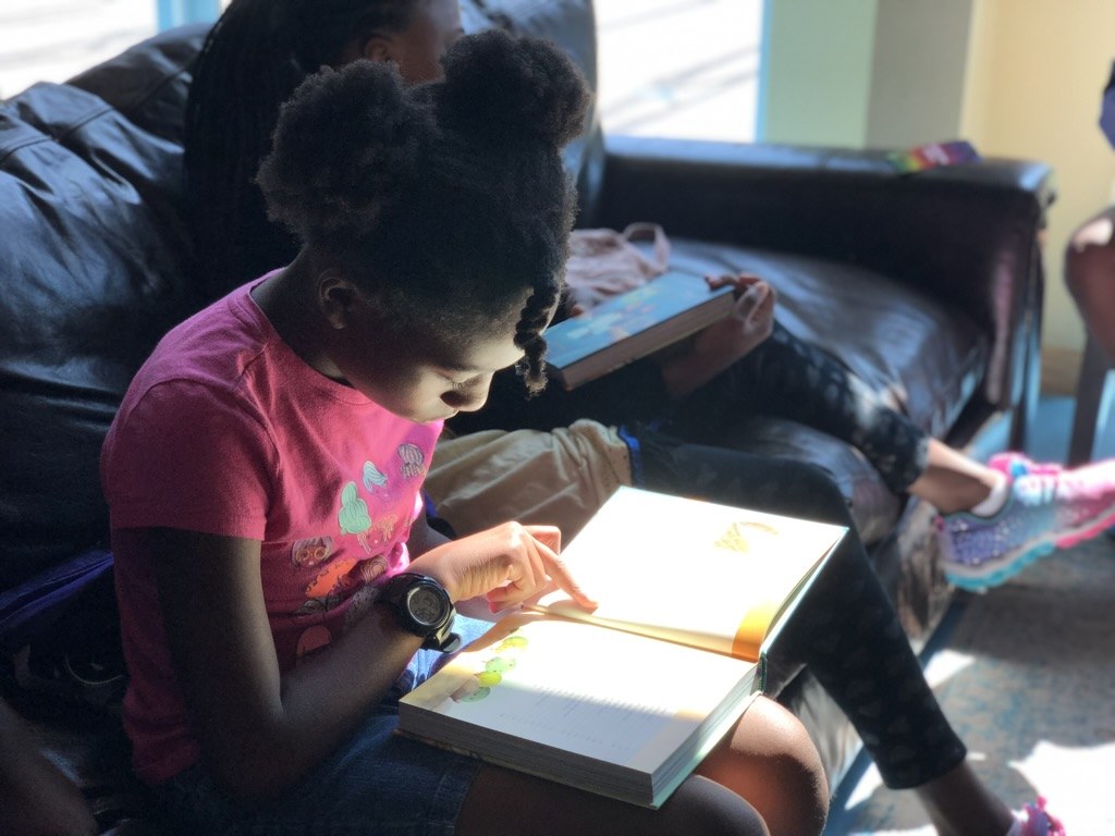 A young Noggin student reading a book at home, absorbed in the story